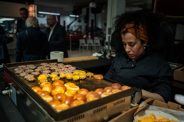 Cheffe en veste noire supervisant une animation plancha