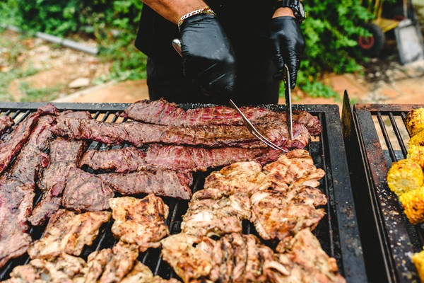 Animation BBQ avec chef grillant viandes marinées et épis de maïs sur barbecue lors d'un événement